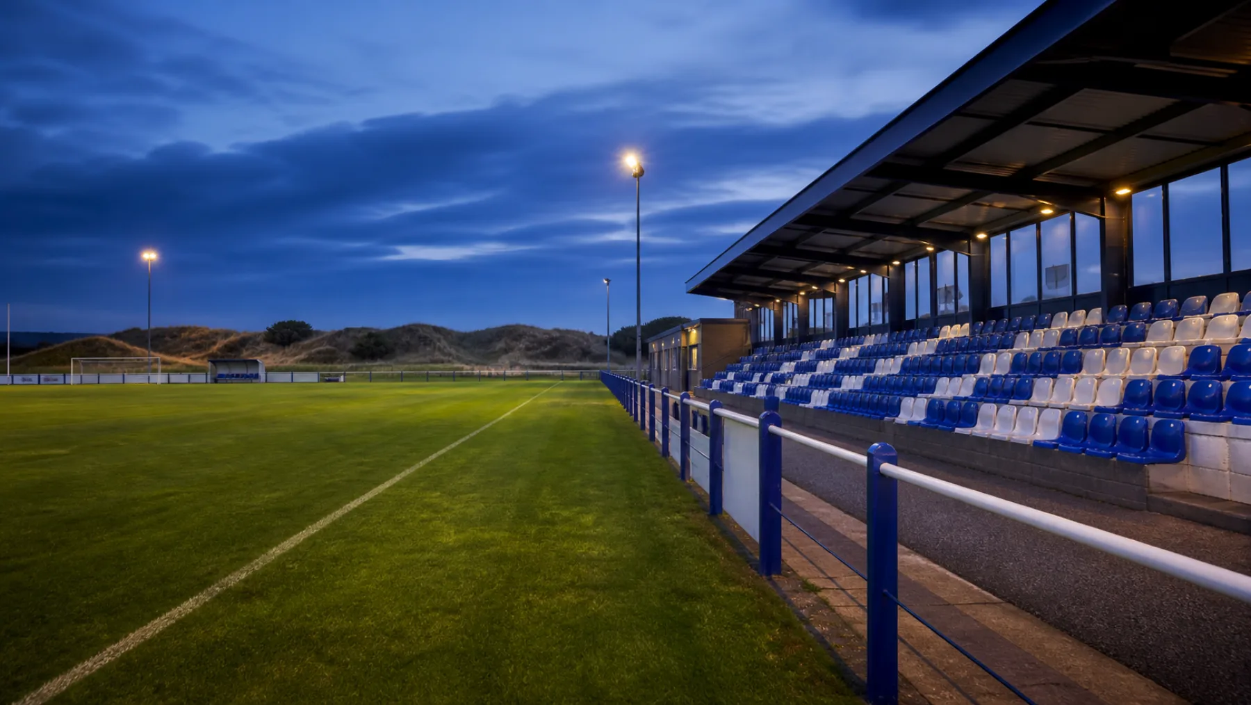 Blauw-wit lokaal voetbalstadion bij avondlicht