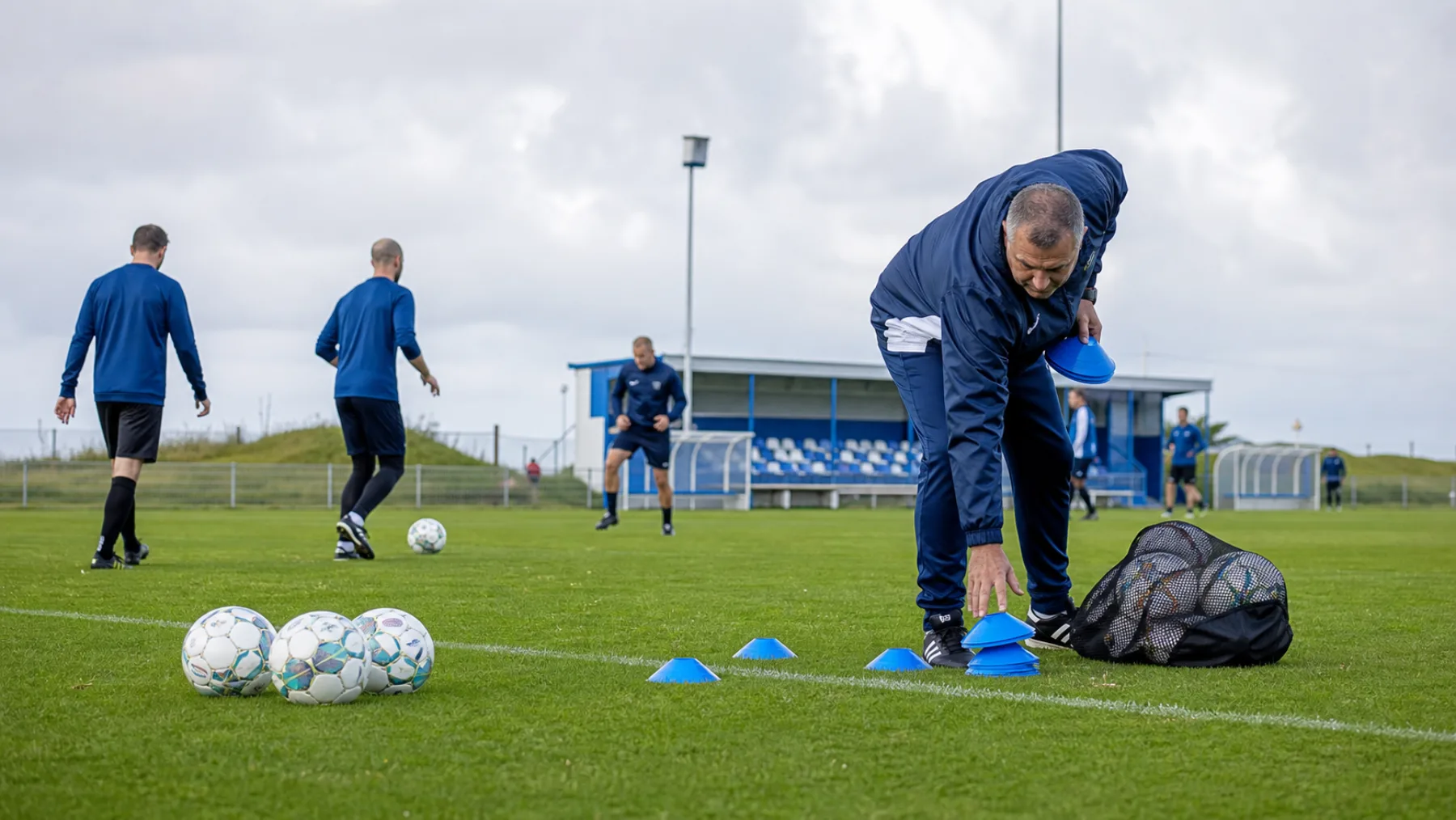 Volwassen spelers en coach bereiden een voetbaltraining voor
